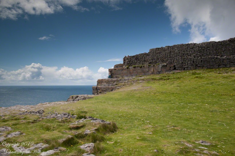 Ancient fort wall with tourists and Cliff Edge of Dun Aonghasa (Dun Aengus)